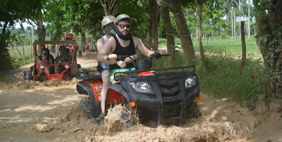 Couple driving an ATV on a muddy road