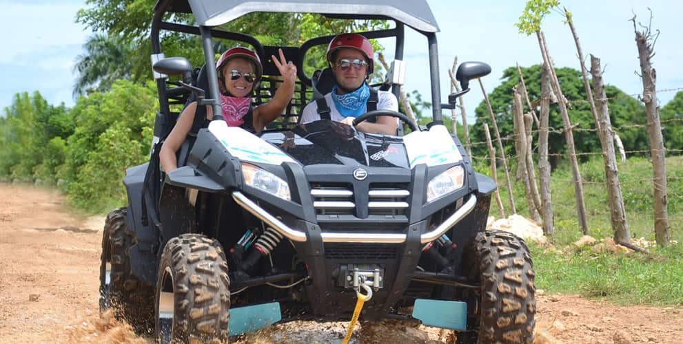 Couple driving an ATV on a muddy road