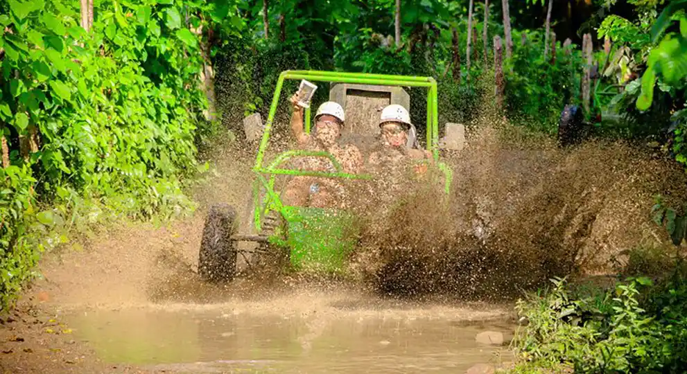 Couple having great time driving a buggie through muddy roads