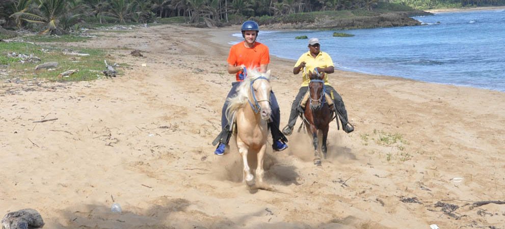Tourist and guide horseback riding on the beach in punta cana