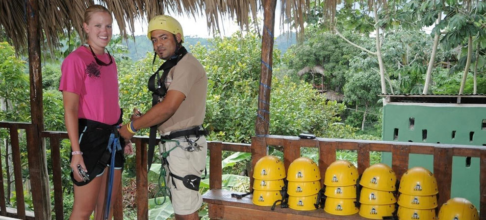 friendly staff assisting tourist zip liner width secure gear